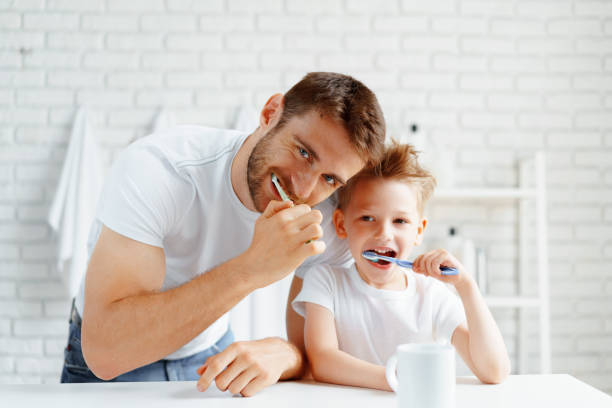 papá y su pequeño hijo cepillando los dientes juntos - brushing teeth fotografías e imágenes de stock