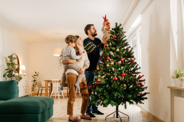 istock Young family of four decorating christmas tree 1286639217