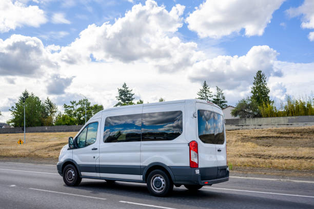 istock Compact commercial mini van with dark glass windows running on the highway road with cloud sky 1286644257