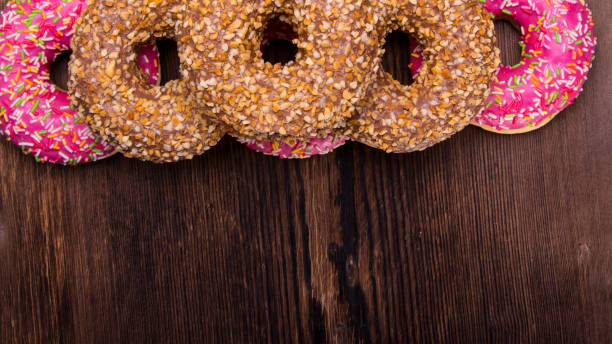 istock Glazed doughnuts with pink chocolate icing with sprinkles on a wooden background,space for text, close - up 1286645498