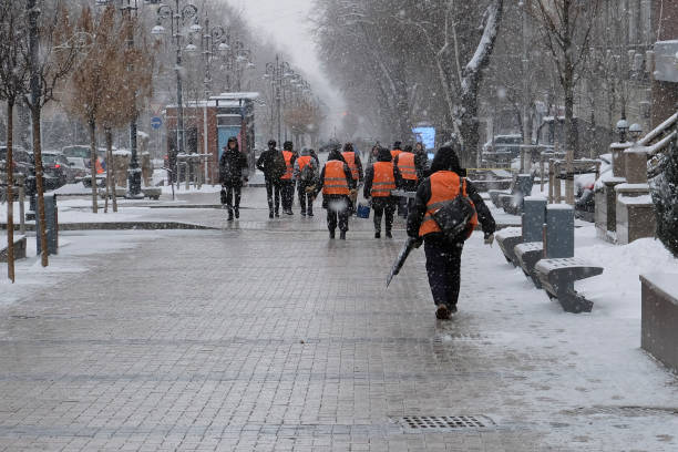 Janitors team are going to clean snow. Workers are going to remove snow in snowfall. Workers with snow shovels in snowfall. 07.03.2020 Almaty, Kazakhstan.