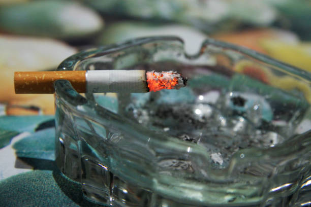 istock Glass ashtray with a burning half smoking cigarette on the table 1286652208