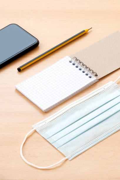 istock A face mask, a blank spiral notepad with a pen and a smartphone are arranged on a wooden table. To-do list concept during the Covid-19 Outbreak. 1286653296