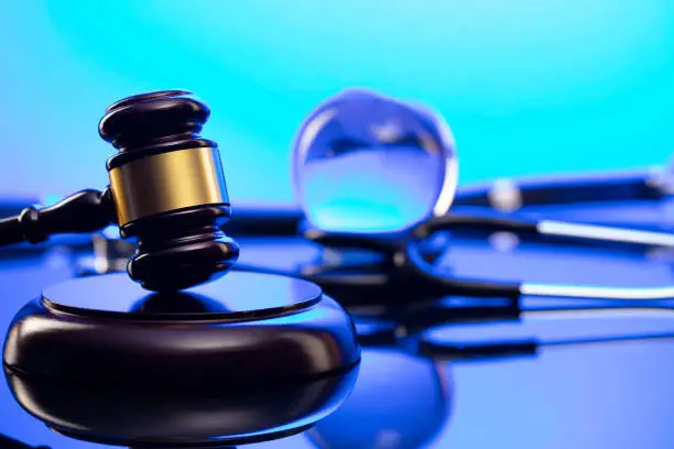 Gavel and stethoscope on the glass table. Blue light.