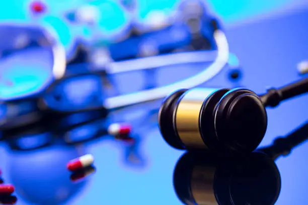 Gavel and stethoscope on the glass table. Blue light.