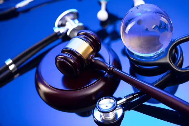 Gavel and stethoscope on the glass table. Blue light.