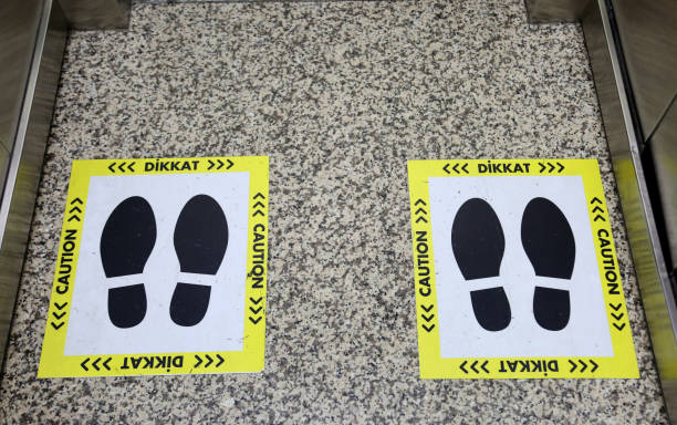 istock Social distance warning in the elevator. Footprint signs with text caution. 1286656473