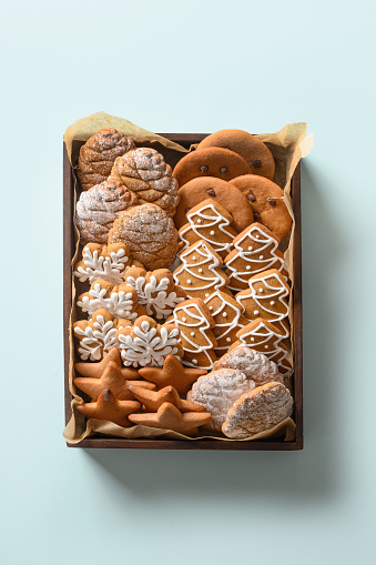 Christmas gingerbread cookies in box as handmade present on blue background. Xmas vertical greeting card. View from above.