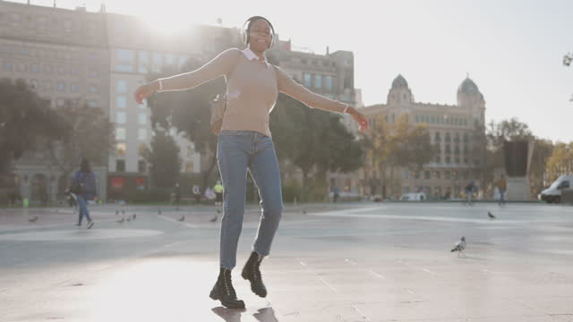 Young Woman with Headphones dancing at city