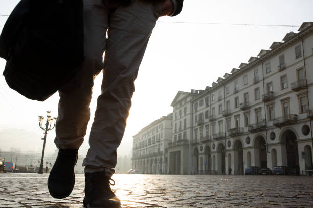 istock Businessman walks down cobblestone street at sunrise 1286659123