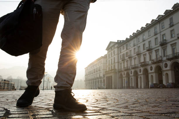 istock Businessman walks down cobblestone street at sunrise 1286659214