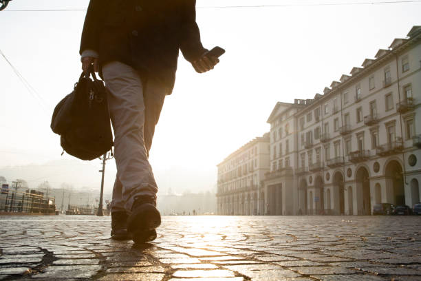 istock Businessman walks down cobblestone street at sunrise 1286659259
