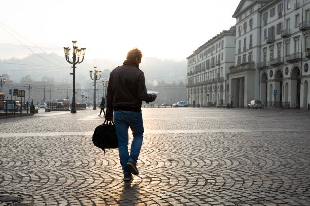 istock Man walks down cobblestone street at sunrise 1286660434