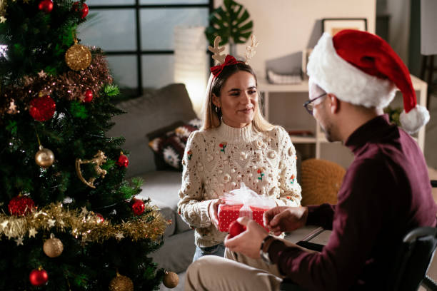 istock Young man surprising his girlfriend with Christmas gift at home. 1286661595