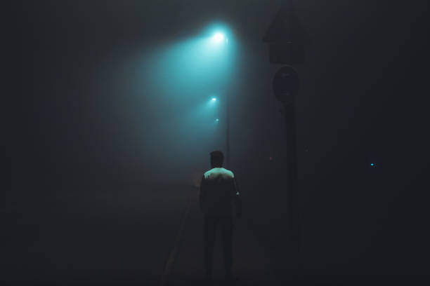 homem esperando sozinho em neblina escura iluminada rua da cidade - teenager dark pensive emotional stress - fotografias e filmes do acervo