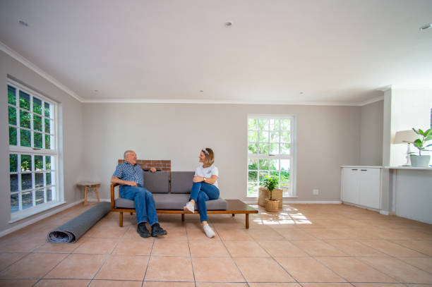 istock Father and daughter sitting smiling and resting on a couch in an empty apartment where daughter is moving into 1286663357