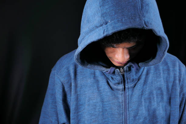 istock sad man in hood looking down isolated on black 1286665775