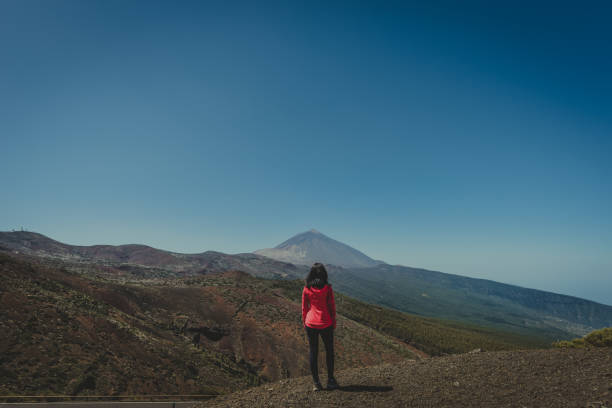 young woman looks to the horizon where a mountain is seen in the background stock photo
