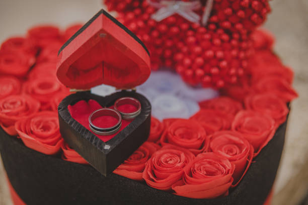 Wedding rings in a box in the shape of a heart and red roses stock photo