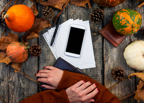 istock Smartphone with blank screen for copy space and notepad on wooden table with pumpkins, fall colorful leaves, autumn composition, Thanksgiving, concept. Top view. 1286672592