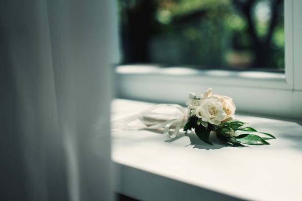 Boutonniere from white roses on the windowsill.