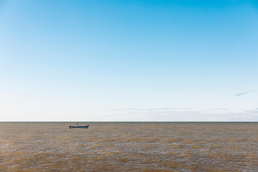 Small boat moored on tranquil sea under a clear blu sky in Caraíva, Northeastern Brazil