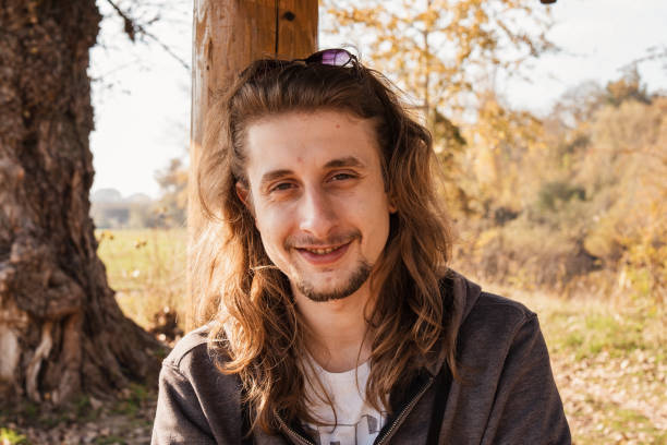istock Beautiful young man sitting in the park and smiling 1286675765
