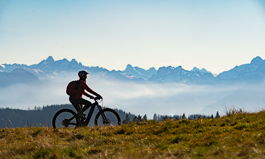 woman on electric mountain bike as silhouette in front of the mountain chain of the Allgaeu High Alps near Oberstdorf, Bavaria