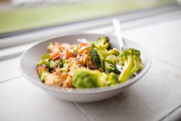 istock Broccoli and chicken salad on white bowl next to a window 1286678572