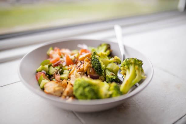 istock Broccoli and chicken salad on white bowl next to a window 1286679101