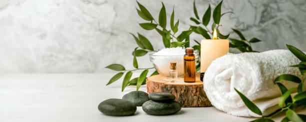 schönheitsbehandlungen für spa-verfahren auf weißem holztisch. massagesteine, ätherische öle und meersalz. kopierraum - spa stock-fotos und bilder