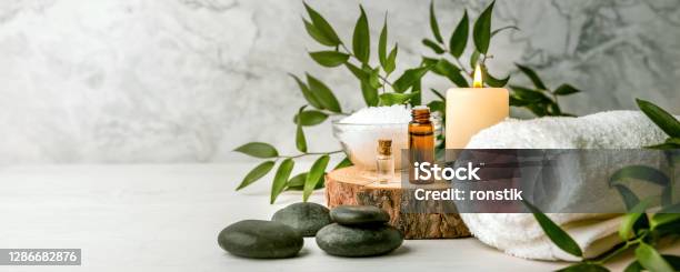 Beauty Treatment Items For Spa Procedures On White Wooden Table Massage Stones Essential Oils And Sea Salt Copy Space Stock Photo - Download Image Now