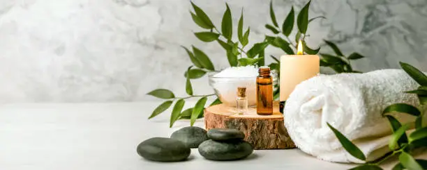 Photo of beauty treatment items for spa procedures on white wooden table. massage stones, essential oils and sea salt. copy space