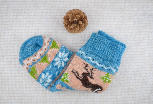 istock Socks and pine cone on white knitted background. Winter holiday concept 1286682895