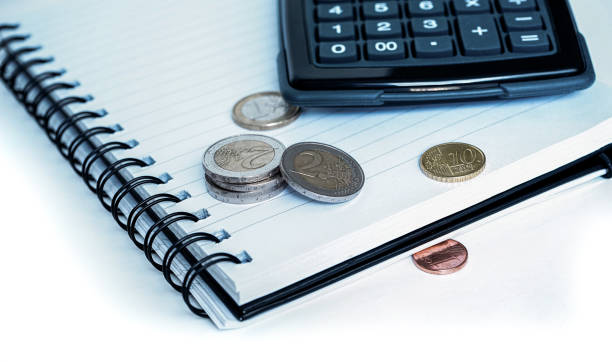 istock White notebook with calculator and coins on white desk at home office 1286683160