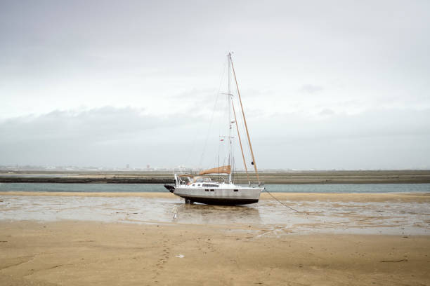 A small boy heading sailing boat on the sand during low tide, Faro, Portugal