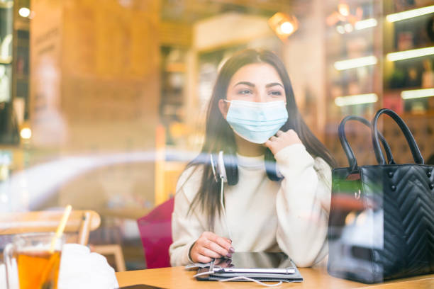 istock A woman with a protective mask in a restaurant photographed through the window 1286688488