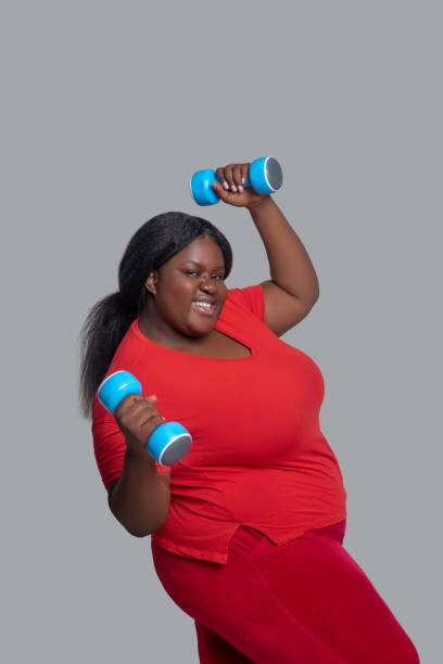 istock Young dark-skinned woman with dumbbells looking energized 1286688815
