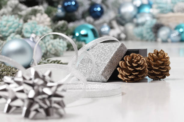 istock merry christmas background, silver gift present box with bow and ribbon, next to blue Christmas balls and pine cones, useful as a greeting card template with copy space 1286689530