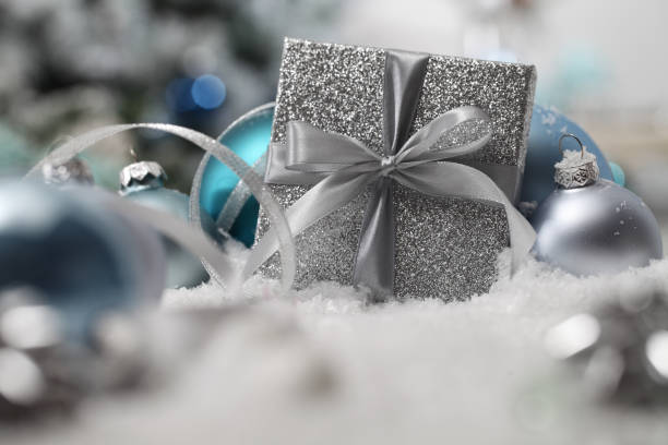 istock merry christmas background, silver gift present box with bow and ribbon, next to blue Christmas balls and snowflakes, useful as a greeting card template with copy space 1286689533