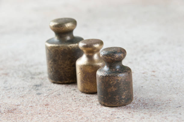 istock Three antique bronze weights for scales on concrete background. 1286689541