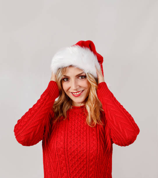 istock Young woman in santa hat smiling and touching hat 1286691254