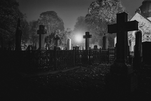 An old graveyard with tombstones at night in black and white. Norra begravningsplatsen, Stockholm.
