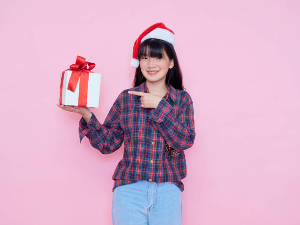 istock Smiling young woman wearing santa hat with holding gift box 1286692492
