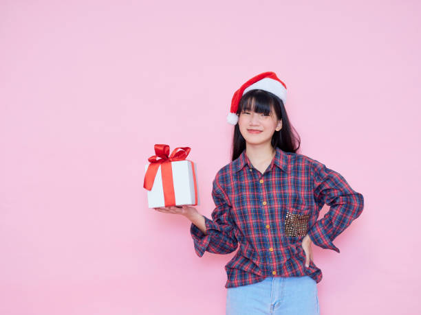 istock Smiling young woman wearing santa hat with holding gift box 1286692511