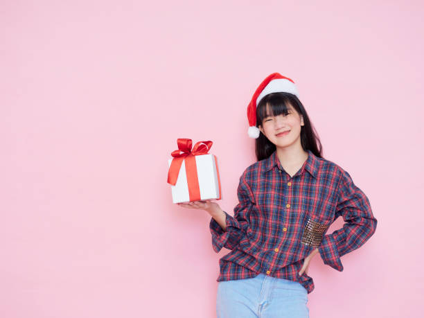istock Smiling young woman wearing santa hat with holding gift box 1286692512