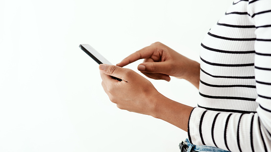 Cropped shot of a woman using a smartphone against a white studio background
