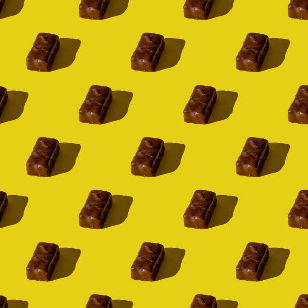 istock small chocolate bar on a yellow background. seamless pattern. Background image. Hard shadow. Top view, flat lay 1286694620