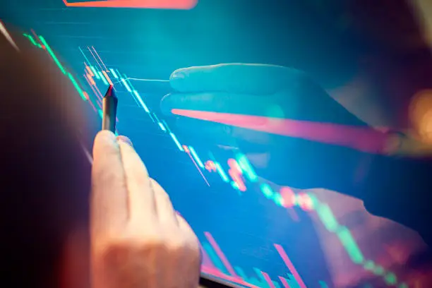 Stockbroker analyzes the financial chart. Online stock exchange on a computer monitor. The economist analyzes the financial graph on the display. A man's hand pointing to an economic chart.