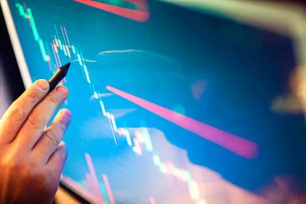 Stockbroker analyzes the financial chart. Online stock exchange on a computer monitor. The economist analyzes the financial graph on the display. A man's hand pointing to an economic chart.